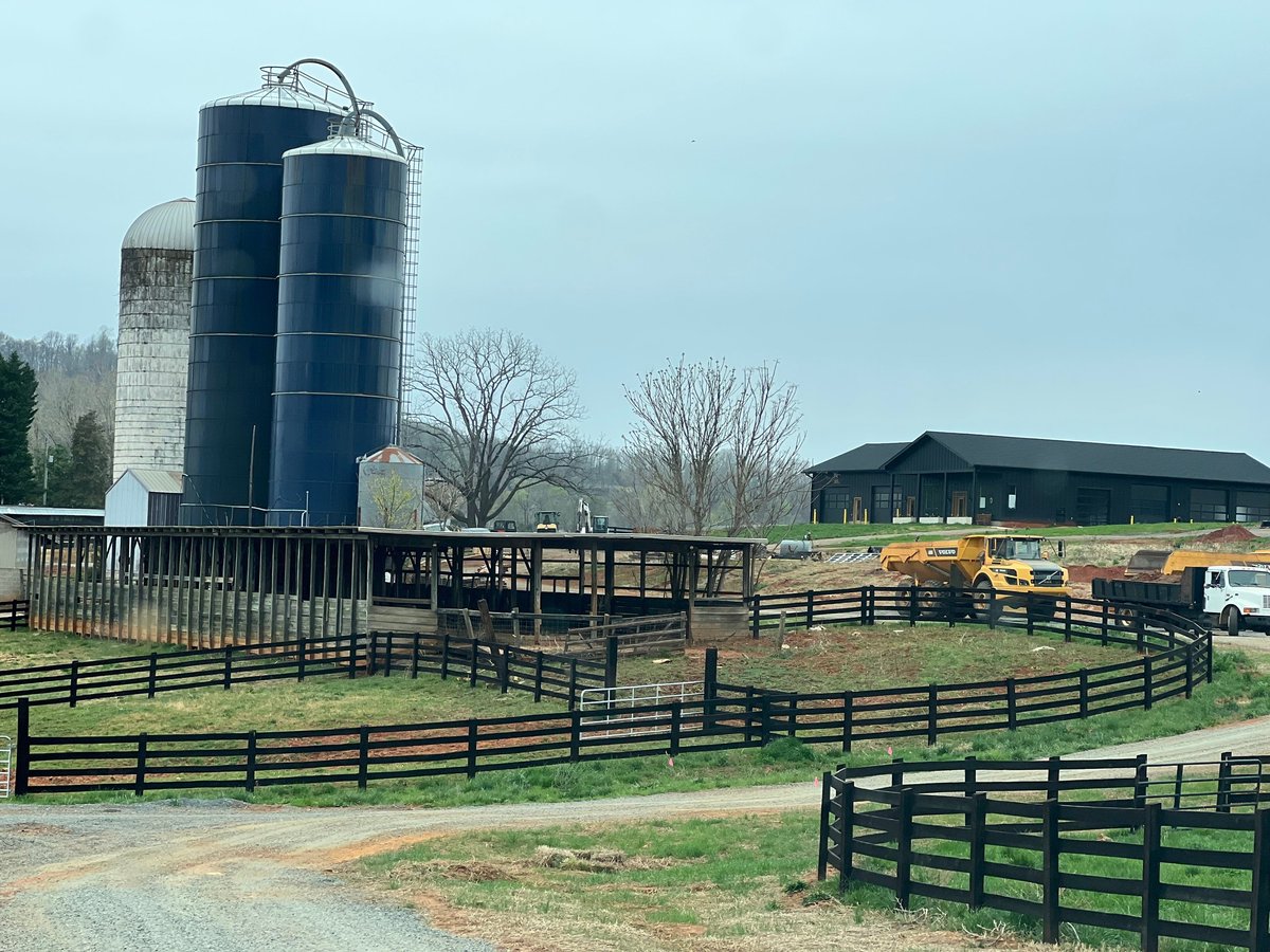 Farm buildings and silos behind black pasture fencing at Alaron Farms